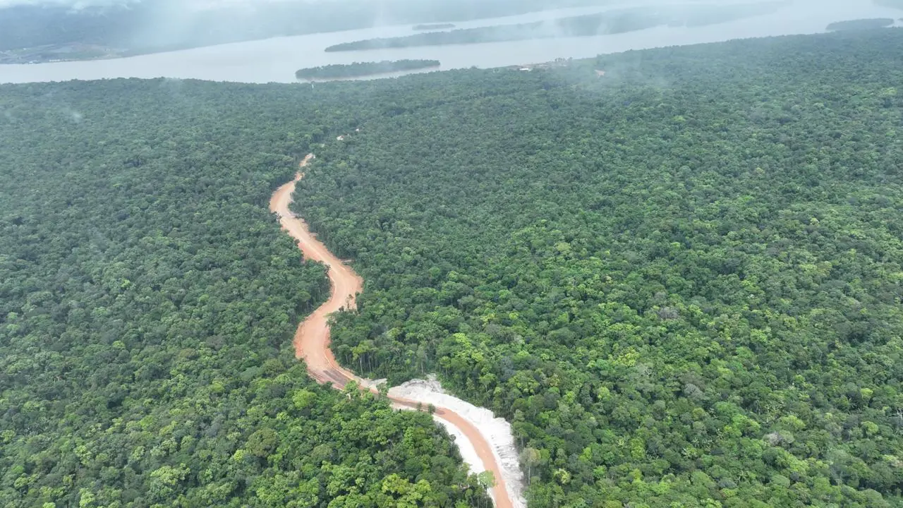 Aerial view of our access road curving through dense rainforest, the Essequibo River in the distance.