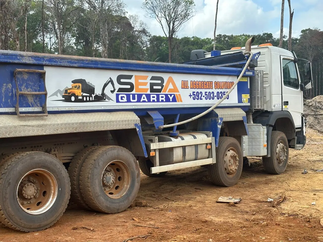 A Volvo tipper in SEBA livery reading "All Aggregate Solutions · +592 503 0359."